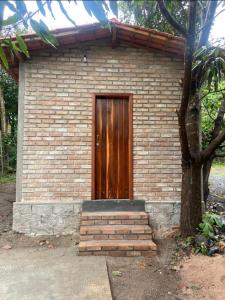 a brick building with a wooden door and stairs at Cantinho HAKUNA MATATA-Vale do Capão a 5 min da Vila in Vale do Capao