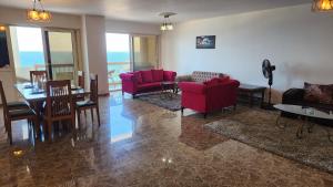 sala de estar con sofás rojos, mesa y sillas en Alex sea view apartment - families only en Alexandria