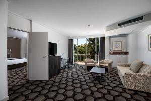 a hotel room with a bed and a living room at Rydges Canberra in Canberra