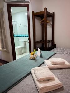 een slaapkamer met een bed met 2 handdoeken en een spiegel bij Villa Bella Ferradura in Búzios