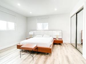 a white bedroom with a bed and two windows at Stylish 4 Bedroom Townhouse in Mid City in Los Angeles