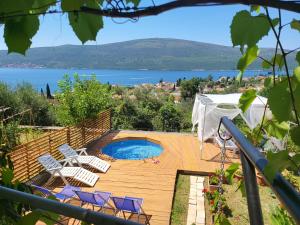 a pool on a wooden deck with chairs and a lake at Sunrise Apartments Baošići in Herceg-Novi