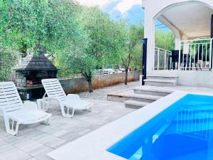 a patio with two chairs and a swimming pool at Adria Holiday Home in Pinezici