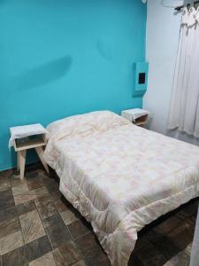 een bed in een kamer met een blauwe muur bij Posadas Amanbay Depto in Posadas