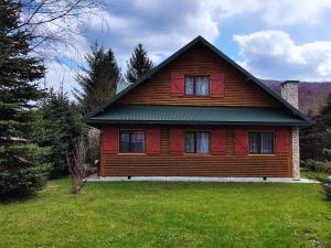 uma casa vermelha com um jardim verde em frente em Ranczo Bieszczady duży Domek z Jacuzzi i Sauną em Mrzygłód