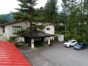 une maison avec deux voitures garées sur un parking dans l'établissement Guest Room Furusatomura Kogeikan, à Omachi