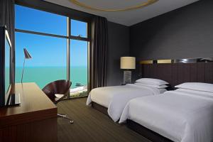 a hotel room with two beds and a large window at Sheraton Batumi Hotel in Batumi