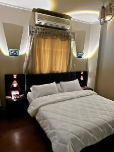 - une chambre avec un grand lit blanc et une fenêtre dans l'établissement The Arabella House - New Cairo, au Caire