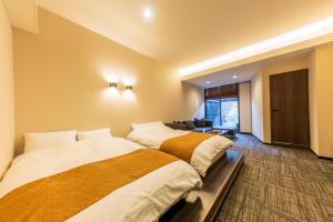 a hotel room with two beds and a couch at Hakone Kuoritei in Hakone