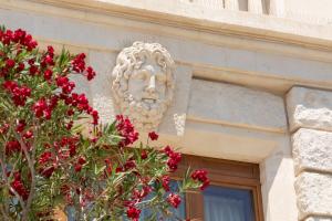 a statue on the side of a building with red flowers at Ortea Palace Hotel, Sicily, Autograph Collection in Siracusa