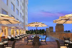 a restaurant with tables and umbrellas next to a pool at Four Points by Sheraton Hotel and Serviced Apartments Pune in Pune