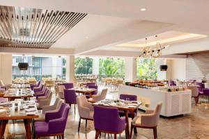 a dining room with tables and purple chairs at Le Meridien Goa, Calangute in Calangute