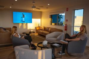 two women sitting in chairs in a living room with a tv at Mackay Adventure Lodge in Mackay