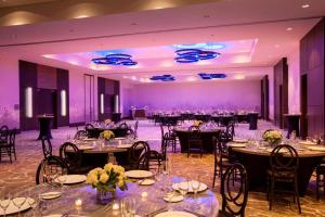 un salón de banquetes con mesas, sillas e iluminación púrpura en The Westin Milwaukee, en Milwaukee