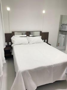un grande letto bianco con lenzuola e cuscini bianchi di Pousada Tropical Paulo Afonso a Paulo Afonso