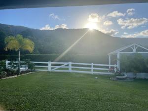 a white fence with the sun shining over a mountain at Ranch Retreat in Kewarra Beach