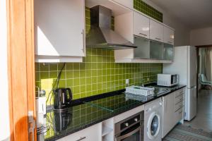 a kitchen with green tiles on the wall at Villas Horizonte Capazi in Porto Santo