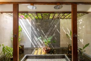 Cette chambre dispose d'une fenêtre avec une plante en pot. dans l'établissement Gili Teak Beach Front Resort, à Gili Trawangan