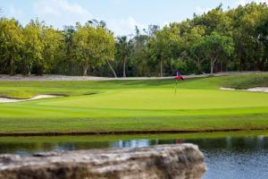 a golf course with a flag on a green at Lumina at The Village Luxury Residences in Corasol in Playa del Carmen