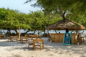 a group of tables and chairs on the beach at Gili Teak Beach Front Resort in Gili Trawangan