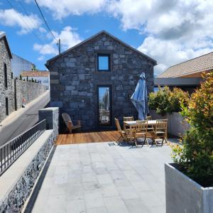 ein Steinhaus mit einer Terrasse mit einem Tisch und Stühlen in der Unterkunft Casas de Campo Lomba D' Água - Turismo Rural in Candelária