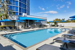 a swimming pool with chairs and blue umbrellas at Four Points by Sheraton Tallahassee Downtown in Tallahassee
