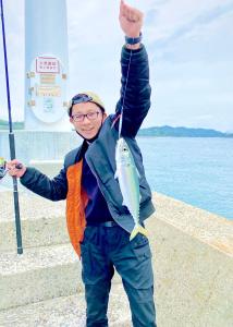 a man holding a fish on a string at なにもない幸せな島のリトリート宿 The Bonds in Matsuyama