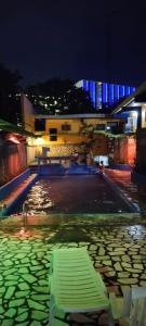 un banco verde sentado en una piscina de agua por la noche en 2 Hotel Saleh en Ángeles