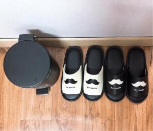 a row of black shoes on a wooden floor at Dam Stay Jeju in Jeju
