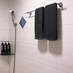 baño con toallas negras colgadas en la pared en Dam Stay Jeju, en Jeju