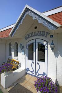 Hotel Seelust في Hennstedt: مبنى ابيض بباب ازرق وزهور