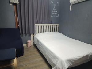 a bedroom with a white bed with a window at Dam Stay Jeju in Jeju