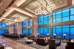 duży hol z krzesłami i stołami oraz dużymi oknami w obiekcie Sheraton Chuzhou Hotel w mieście Chuzhou