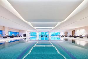 a swimming pool in a building with chairs and water at Sheraton Chuzhou Hotel in Chuzhou
