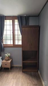 Dam Stay Jeju في جيجو: غرفة نوم مع خزانة ونافذة
