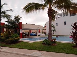 a hotel with a swimming pool and a palm tree at Maktub Casa AcaCancún in Barra Vieja