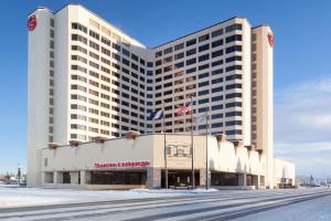 een groot hotelgebouw met sneeuw ervoor bij Sheraton Anchorage Hotel in Anchorage