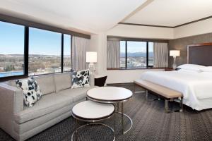 a hotel room with a bed and a couch and windows at Sheraton Anchorage Hotel in Anchorage