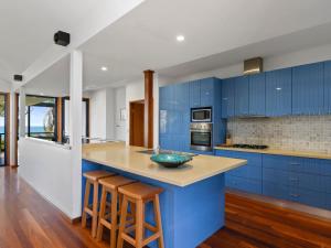Arrawarra的住宿－Surf Break，厨房配有蓝色橱柜和带凳子的台面