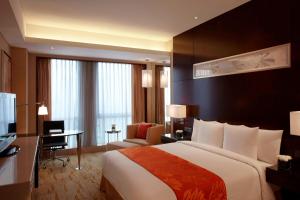 a hotel room with a large bed and a desk at Courtyard by Marriott Shanghai Jiading in Jiading