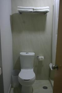 a bathroom with a toilet and towels on a shelf at Hotel Urbainn in Veracruz