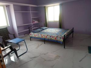 a bedroom with a bed and a chair and two windows at Sathya Sai Nivas in Puttaparthi