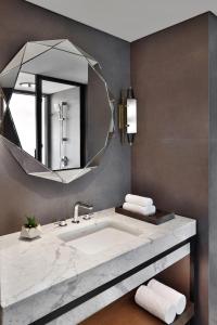 uma casa de banho com um lavatório e um espelho em Port Muziris, A Tribute Portfolio Hotel em Nedumbassery