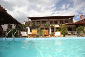 a swimming pool with chairs and a house in the background at Akropolis Guest House in Bergama