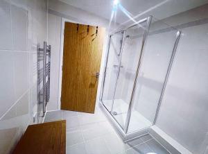 a bathroom with a shower and a wooden door at The Chic Nexus Apartment 2023 New-Build in Oxford