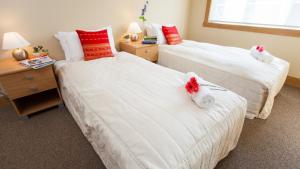 two beds in a room with red and white pillows at Kamakura Apartments in Niseko