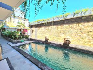 a swimming pool in front of a brick wall at Kamandaka in Kuta