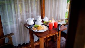 a table with a plate of food and drinks on it at Tirta Jenar Villas in Tegalalang
