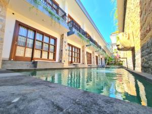 a swimming pool in the courtyard of a building at Kamandaka Living in Kuta