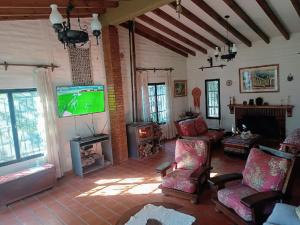 ein Wohnzimmer mit einem TV, einem Sofa und Stühlen in der Unterkunft Complejo Los Aromos, San Juan, AR in San Juan